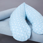 Das KraftKids qualitäts Stillkissen weiße Pfeile auf Blau mit ergonomischer Form ruht auf einer hellblau gepolsterten Bank mit Holzbeinen, die vor einem grauen Hintergrund stehen.