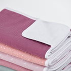 Ein ordentlich gefalteter Stapel KraftKids Wickelunterlage Musselin purpur Babydecken in weichen, farbenfrohen Mustern mit weißem Rand - mit einer wasserabweisenden Unterlage für Komfort und Bequemlichkeit.