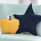 Ein hellblauer Polsterstuhl mit einem gelben Apfelkissen und einem KraftKids Sternkissen Musselin dunkelblau sitzt vor einem weißen Schrank - perfekt, um jedem Kinderzimmer Charme zu verleihen.