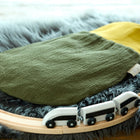 Ein KraftKids Strampelsack Frühling Sommer Doppelkrepp Grün Herbstgrün Babyschlafsack steht auf einem flauschigen grauen Teppich, umgeben von einer hölzernen Spielzeugeisenbahnstrecke mit einem weißen Spielzeugeisenbahnzug.