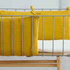 Das KraftKids Bettumrandung Nestchen Doppelkrepp Gelb Mustard ist ein modernes Kinderbett mit Metallrahmen und Holzfüßen, das mit einer weißen Matratze vor einem schlichten hellgrauen Hintergrund ausgestattet ist.