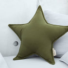 Das KraftKids Sternkissen Doppelkrepp Grün Herbstgrün liegt auf hellgrauen Kissen auf einem hellen Sofa vor einer Betonwand - ein besonderer Hingucker fürs Kinderzimmer.