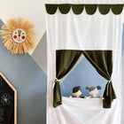 Ein verspieltes Kinderzimmer mit einer Sonnenwanddekoration, einer Kreidetafel mit der Aufschrift ZOE und dem KraftKids Puppentheater Kasperletheater Doppelkrepp Grün Herbstgrün inkl. Teleskopstange. Teleskopstange mit zwei Plüschtierpuppen hinter grünen Vorhängen.