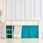 Ein Kura Hochbett mit KraftKids Hochbettvorhänge Set 2+1 aus Musselin mit goldenen Punkten auf Petrol steht vor einer weißen, getäfelten Wand. Darunter zwei weiße Bälle, links ein Korb mit Pampasgras, rechts zwei Holz-Würfelhocker.