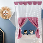Das KraftKids Puppentheater Kasperletheater Musselin rosa incl. Teleskopstange mit rosa Musselinvorhängen, zwei Puppen, einem Wandbehang mit Löwengesicht und einer Kreidetafel mit Kritzeleien vor einem blau-grauen, geometrischen Hintergrund.