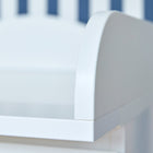 Nahaufnahme des weißen Wickelaufsatzes von KraftKids, passend für schmale 3er oder 4er MALM Kommode mit geschwungenen Kanten, vor blau-weiß gestreiftem Hintergrund.